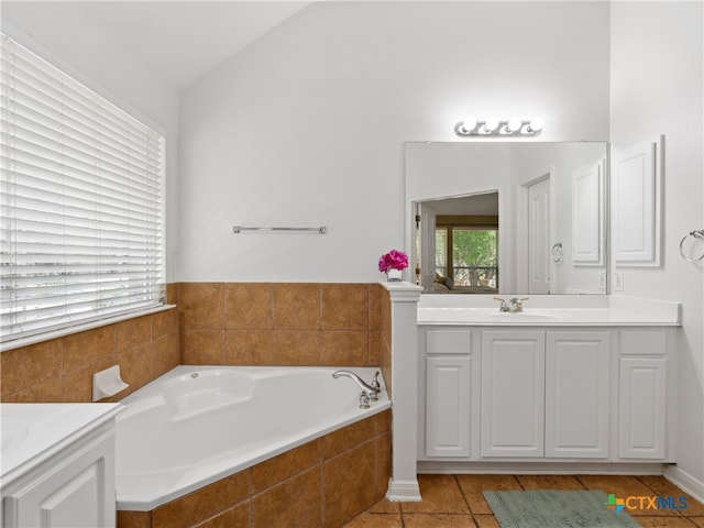 bathroom featuring vanity, lofted ceiling, a relaxing tiled tub, and tile patterned floors