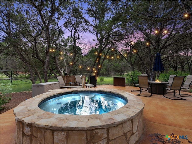 pool at dusk with a patio area, a hot tub, and an outdoor fire pit