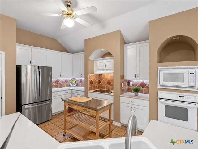 kitchen featuring sink, white appliances, tasteful backsplash, white cabinets, and vaulted ceiling