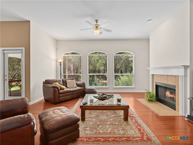 living room featuring hardwood / wood-style flooring, a tile fireplace, and ceiling fan