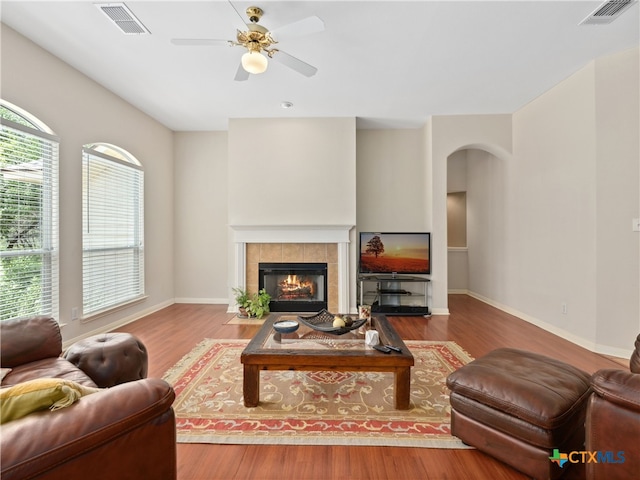 living room with hardwood / wood-style flooring, a tile fireplace, and ceiling fan