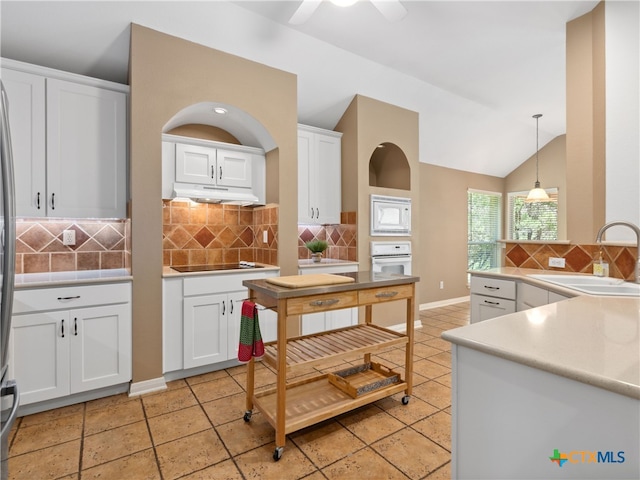 kitchen featuring sink, vaulted ceiling, hanging light fixtures, white appliances, and white cabinets