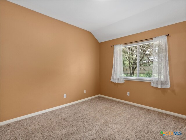 carpeted empty room featuring vaulted ceiling