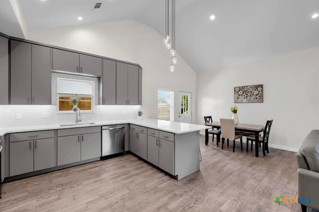 kitchen featuring dishwasher, kitchen peninsula, sink, pendant lighting, and light wood-type flooring