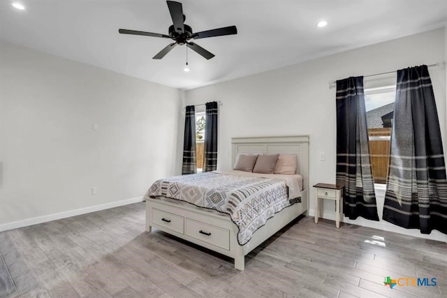 bedroom featuring ceiling fan, multiple windows, and light hardwood / wood-style floors