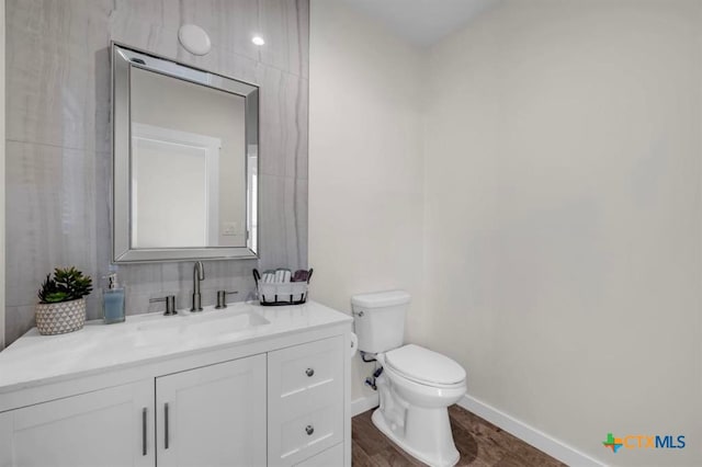 bathroom with toilet, vanity, and wood-type flooring