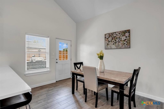 dining space featuring hardwood / wood-style flooring and high vaulted ceiling