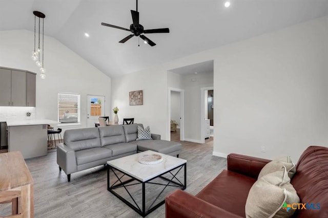 living room with light wood-type flooring, ceiling fan, and high vaulted ceiling