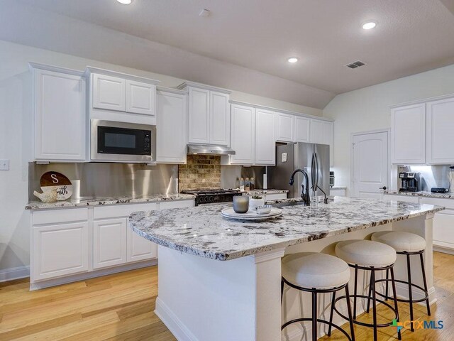599 Mission Hill Run, New Braunfels, TX 78132 - kitchen with built in microwave, under cabinet range hood, freestanding refrigerator, a sink, and a center island with sink