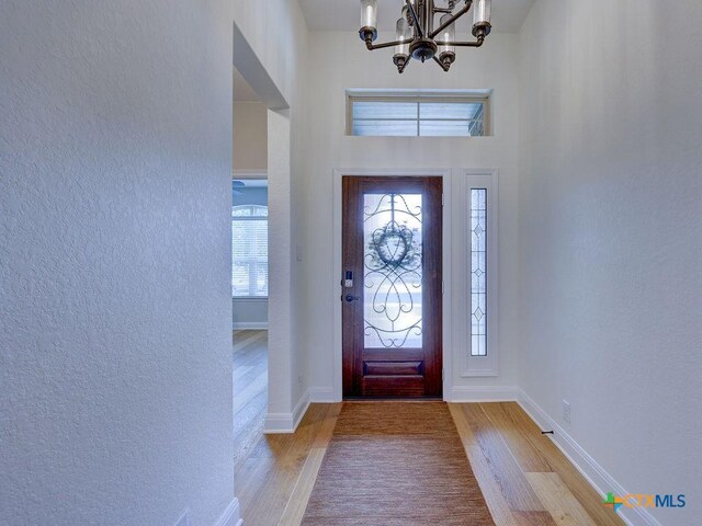 599 Mission Hill Run, New Braunfels, TX 78132 - entrance foyer with wood finished floors, a chandelier, a textured wall, and baseboards