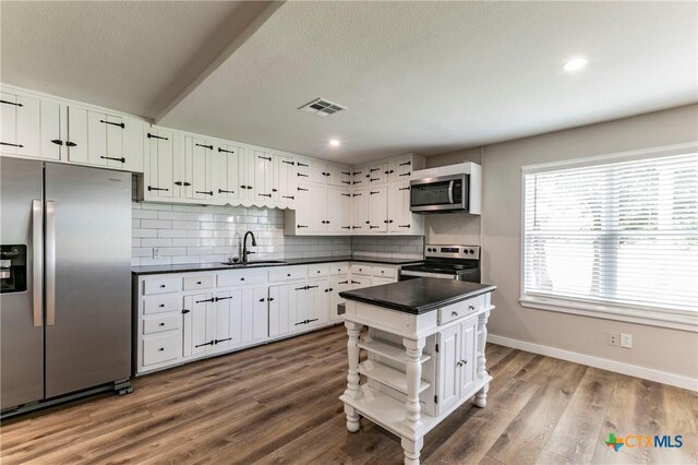14380 Spotted Horse Ln, Salado, TX 76571 - kitchen with open shelves, dark countertops, visible vents, appliances with stainless steel finishes, and a sink