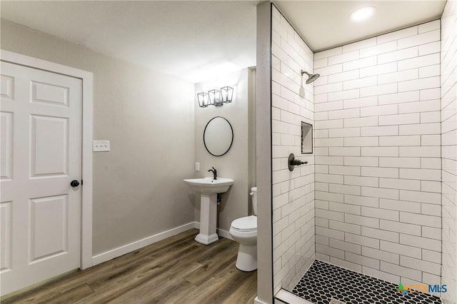 14380 Spotted Horse Ln, Salado, TX 76571 - bathroom featuring baseboards, toilet, wood finished floors, a tile shower, and a sink