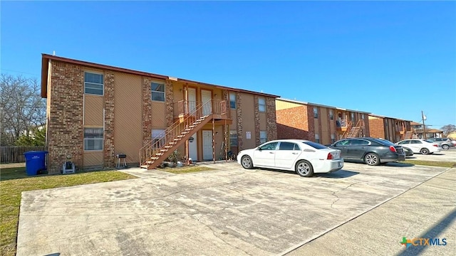 view of property featuring uncovered parking and stairway