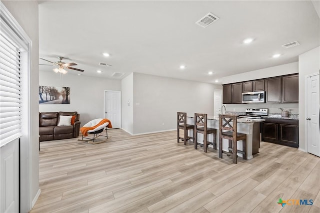 8903 Cantera Ridge Rd, Temple, TX 76502 - kitchen featuring light wood-style floors, dark brown cabinets, ceiling fan, a center island with sink, and recessed lighting