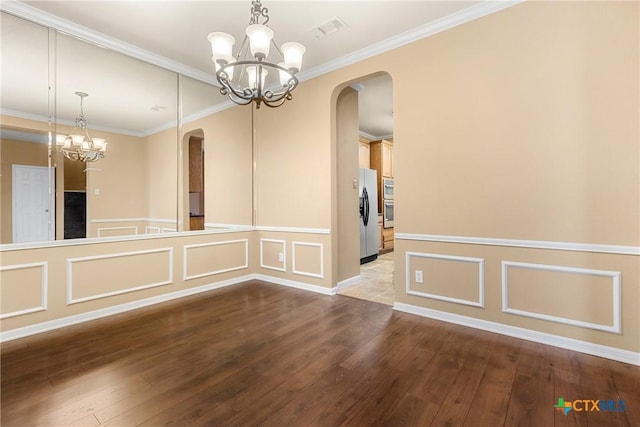 empty room featuring crown molding, hardwood / wood-style flooring, and an inviting chandelier