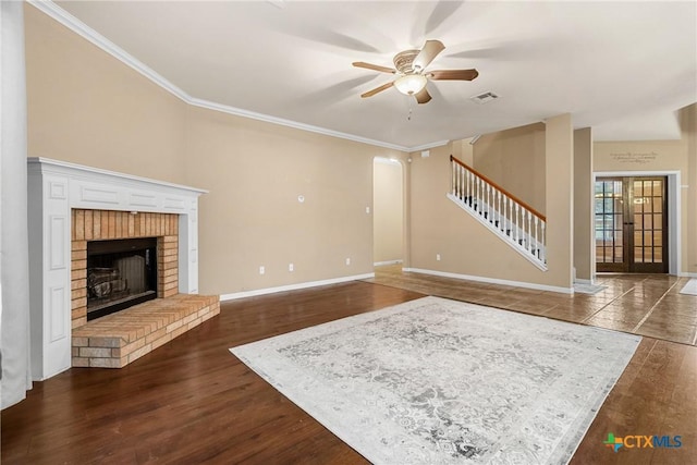 unfurnished living room featuring french doors, a brick fireplace, ceiling fan, dark hardwood / wood-style floors, and ornamental molding