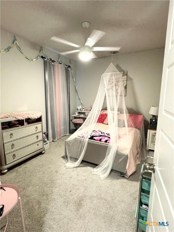 carpeted bedroom with ceiling fan and a textured ceiling