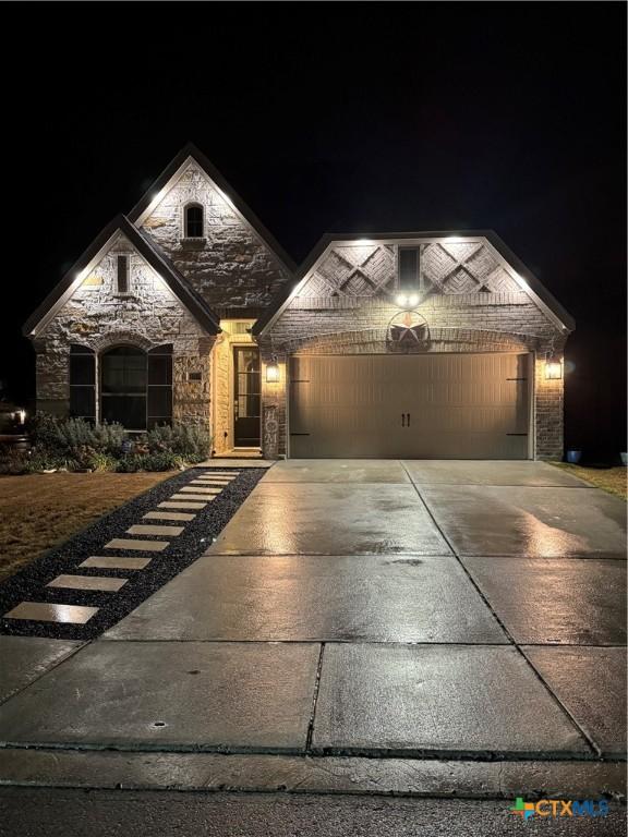 view of front of house with a garage, stone siding, brick siding, and concrete driveway