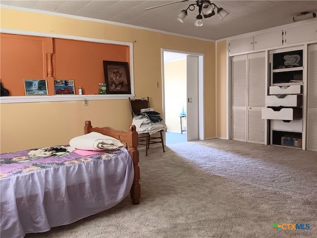 bedroom with carpet, ceiling fan, ornamental molding, and a closet