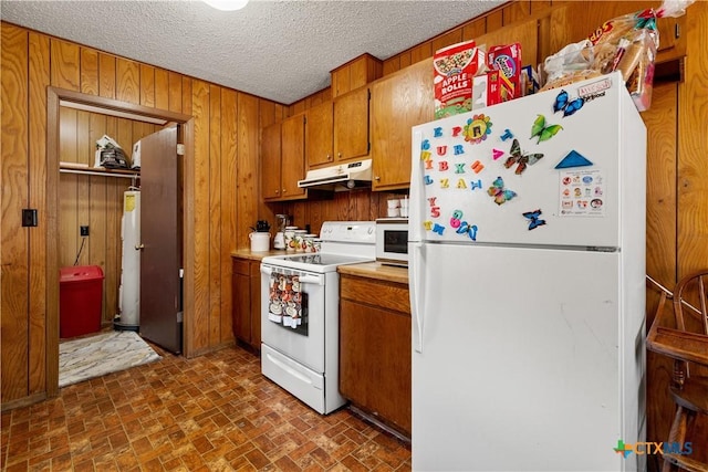 kitchen with wood walls, gas water heater, white appliances, and a textured ceiling