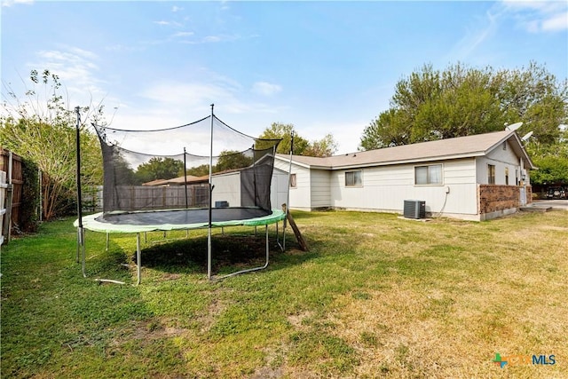 view of yard with a trampoline and central AC