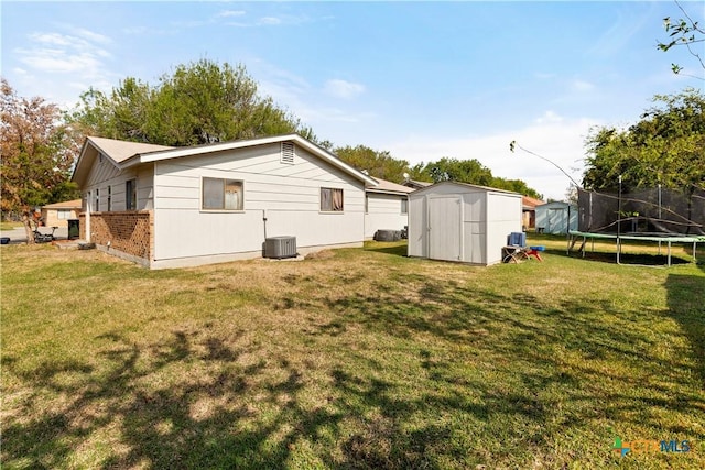 back of house with a yard, cooling unit, a shed, and a trampoline