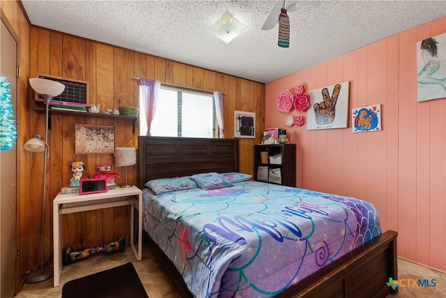 bedroom featuring a textured ceiling, ceiling fan, and wooden walls