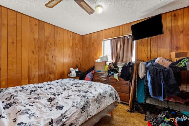 carpeted bedroom with ceiling fan, wood walls, and a textured ceiling