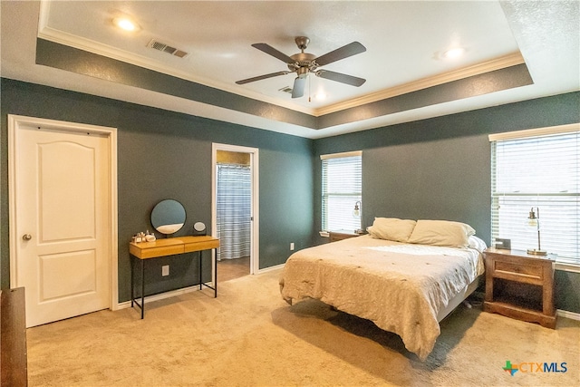 bedroom with a tray ceiling, crown molding, ceiling fan, and light colored carpet