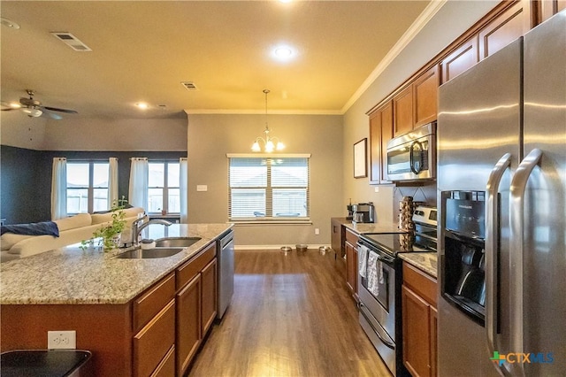 2529 Nolan Creek St, Temple, TX 76504 - kitchen with stainless steel appliances, brown cabinetry, dark wood-style floors, a kitchen island with sink, and ornamental molding