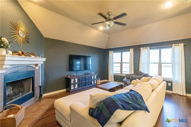 living room with a tiled fireplace, ceiling fan, dark hardwood / wood-style floors, and lofted ceiling