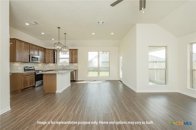 kitchen featuring a center island, lofted ceiling, stainless steel appliances, hanging light fixtures, and dark hardwood / wood-style floors