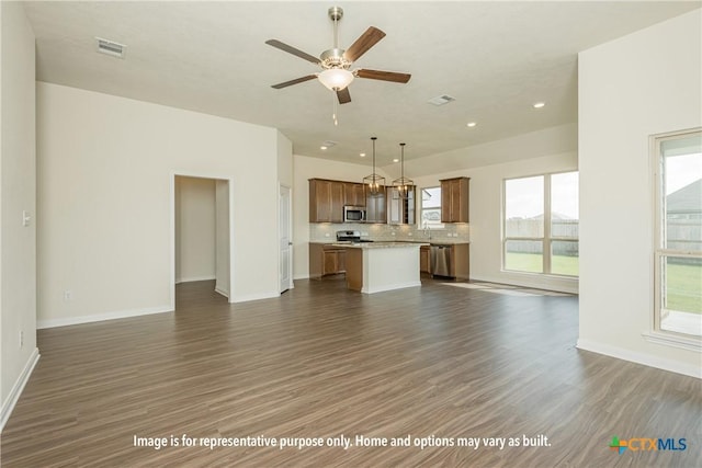 unfurnished living room featuring dark wood-type flooring and ceiling fan