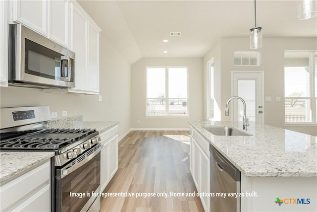 kitchen featuring white cabinetry, sink, hanging light fixtures, stainless steel appliances, and a center island with sink