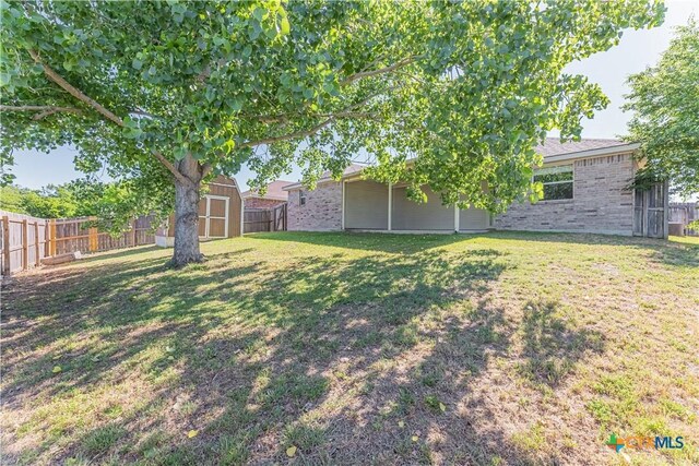 view of yard featuring a fenced backyard, a storage unit, and an outdoor structure