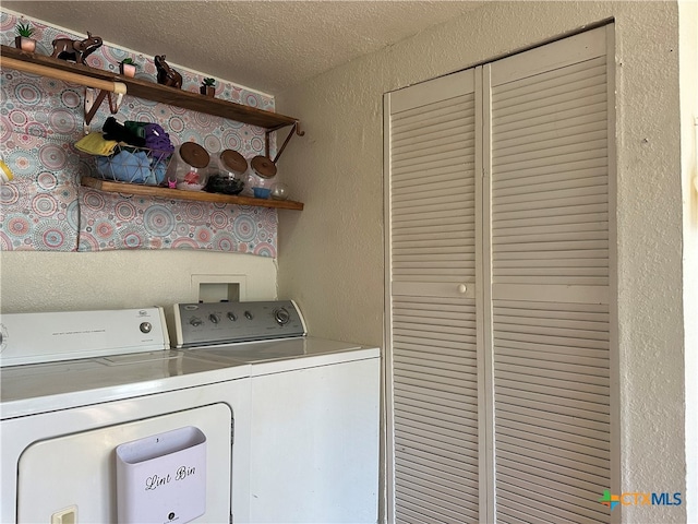 clothes washing area with a textured ceiling and washer and clothes dryer