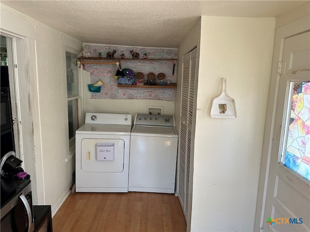 laundry area featuring washing machine and dryer, a textured ceiling, and light hardwood / wood-style floors