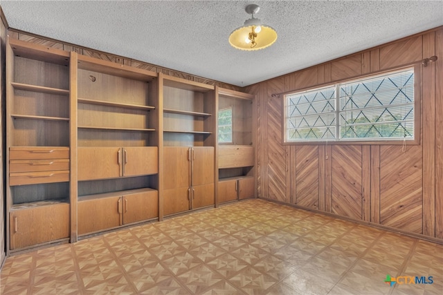 empty room with wood walls and a textured ceiling