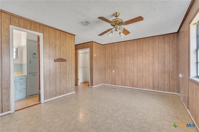 unfurnished bedroom with wood walls, a textured ceiling, and ceiling fan