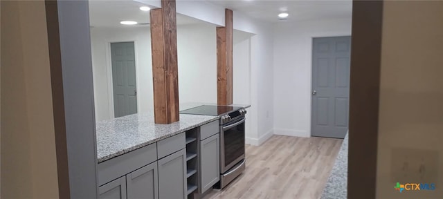 kitchen featuring light hardwood / wood-style floors, stainless steel range with electric cooktop, light stone counters, and gray cabinets