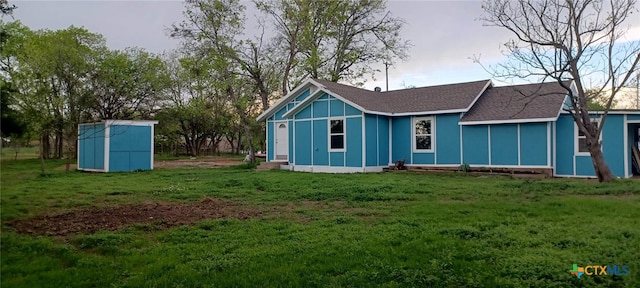 rear view of house featuring a yard and a storage shed