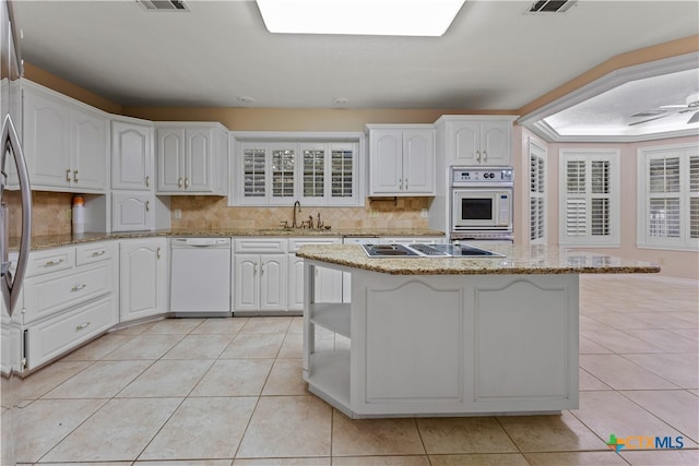 kitchen with white appliances, white cabinets, sink, decorative backsplash, and light tile patterned flooring