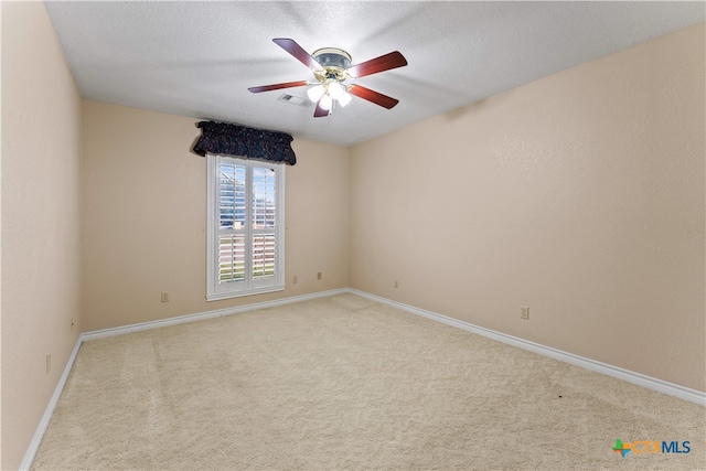 spare room featuring a textured ceiling, ceiling fan, and light carpet