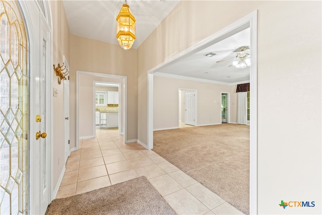 carpeted entrance foyer with ceiling fan and ornamental molding