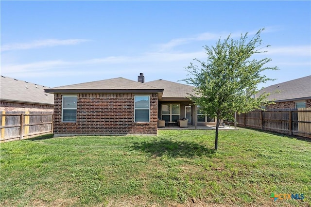 rear view of property featuring brick siding, a fenced backyard, a yard, and a patio area
