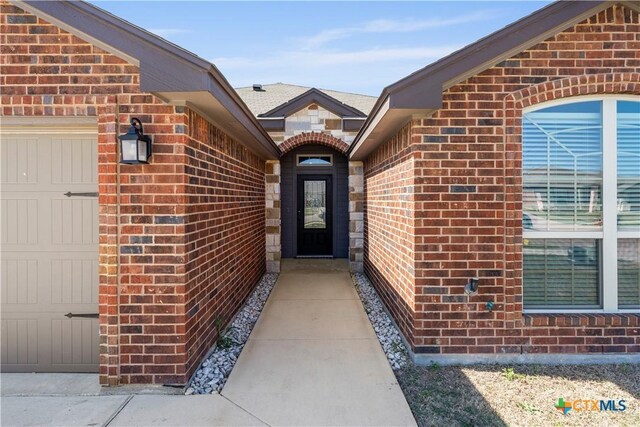 entrance to property with a garage and brick siding