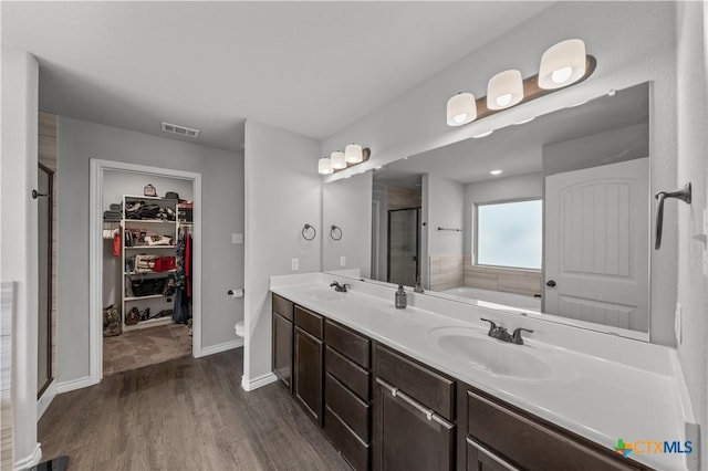 bathroom featuring a sink, visible vents, a stall shower, and wood finished floors