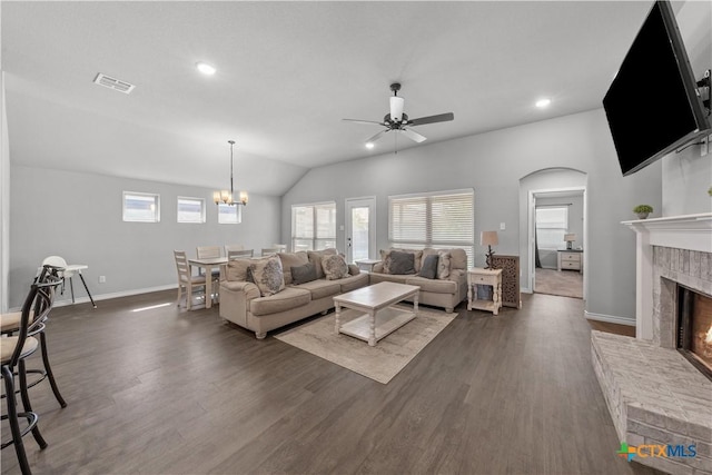 living room with visible vents, ceiling fan with notable chandelier, a brick fireplace, and dark wood-style floors