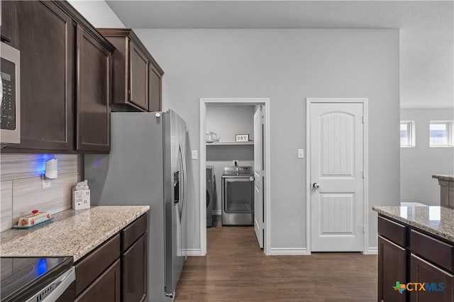 kitchen featuring dark brown cabinetry, light stone counters, dark wood-style flooring, washing machine and clothes dryer, and appliances with stainless steel finishes