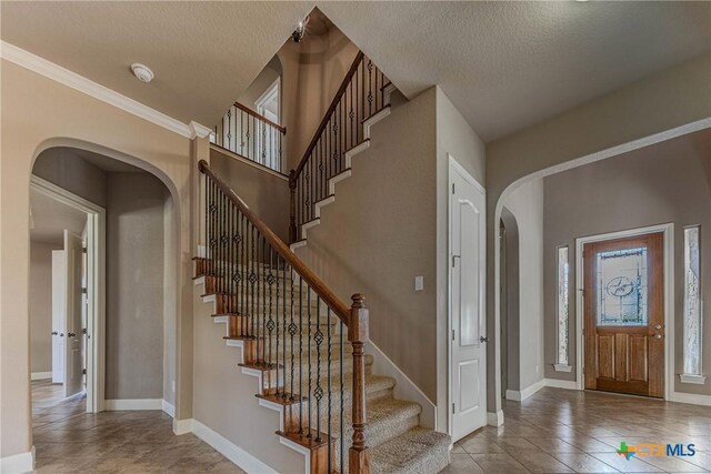 foyer featuring crown molding, light tile patterned floors, and a textured ceiling